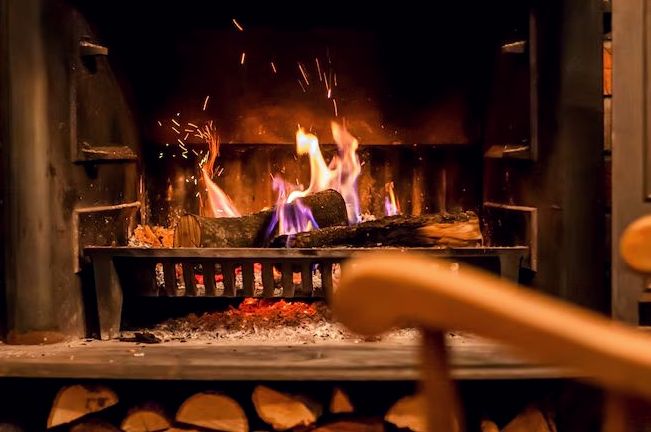 Fire crackling in a grate above a stocked log store