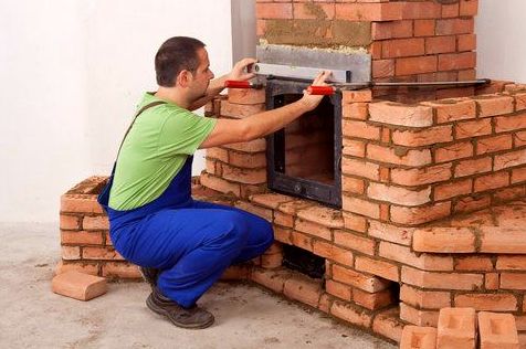 Mason leveling a firebox door in fresh brickwork